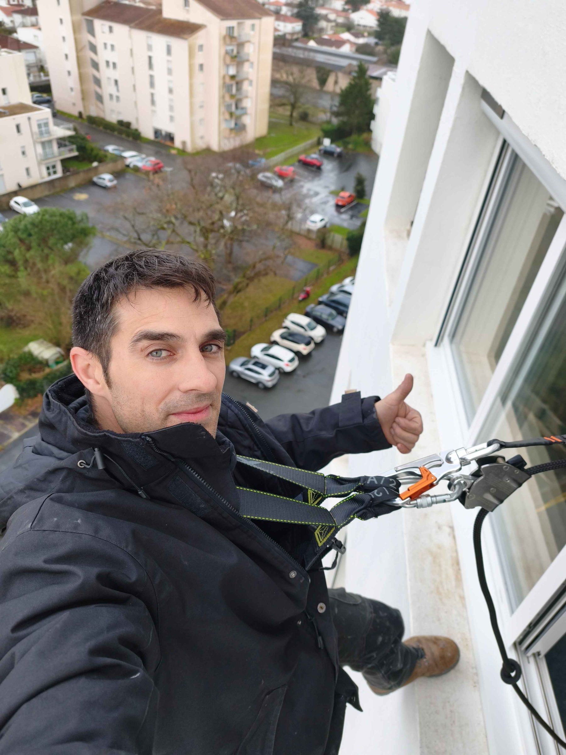 Poseur LUZ installant une fenêtre en hauteur, harnais de sécurité